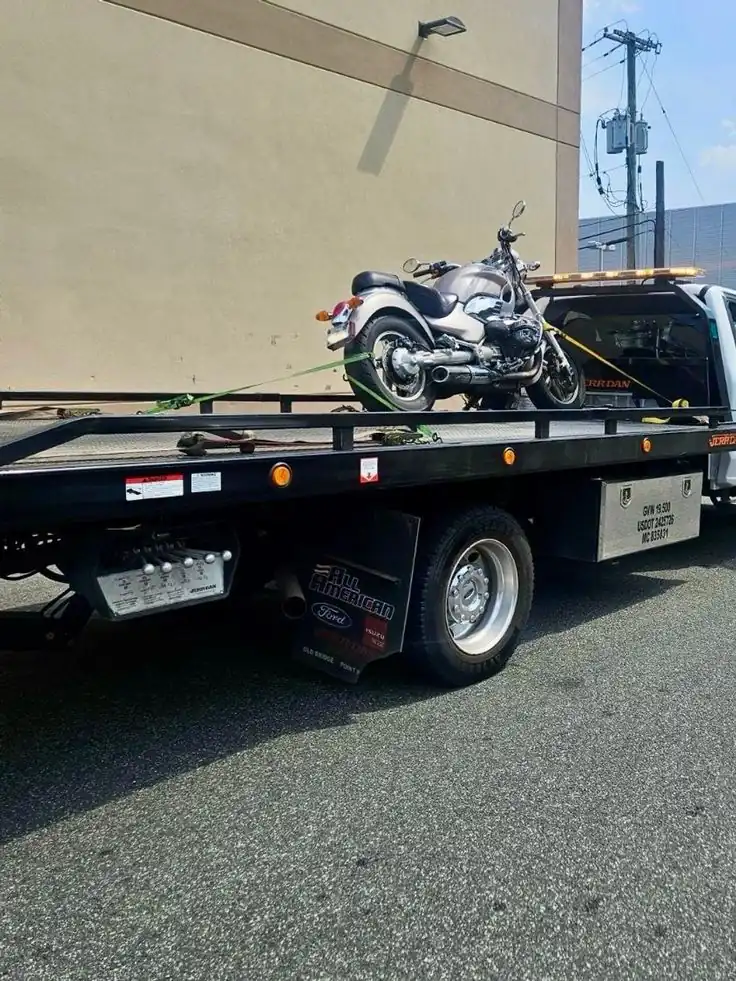 Motorcycle recovery — cruiser motorcycle secured on flatbed with soft-strap tie-down